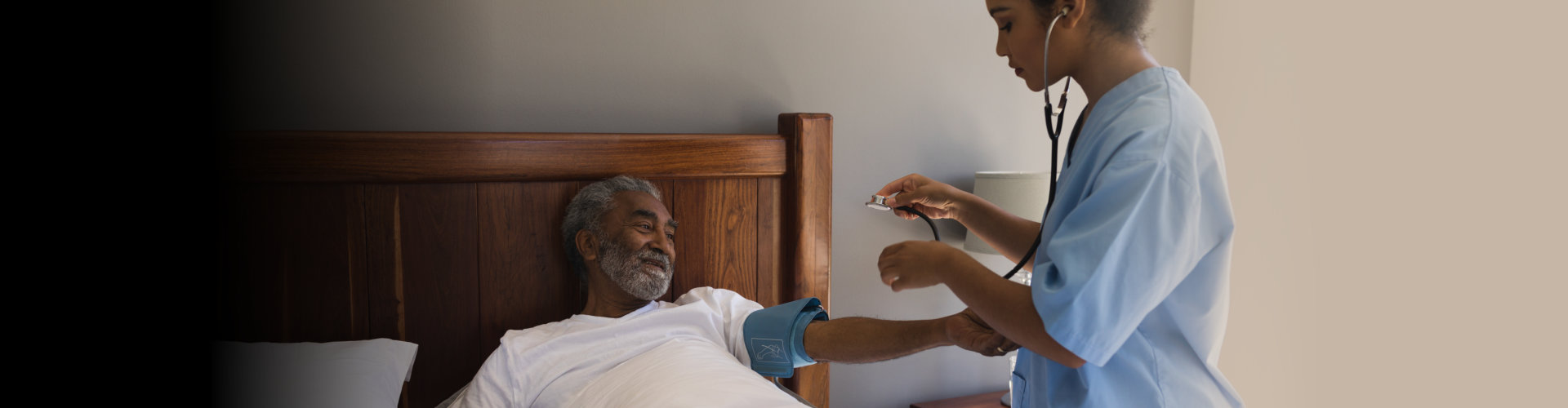 doctor measuring blood pressure of senior man in bedroom at home
