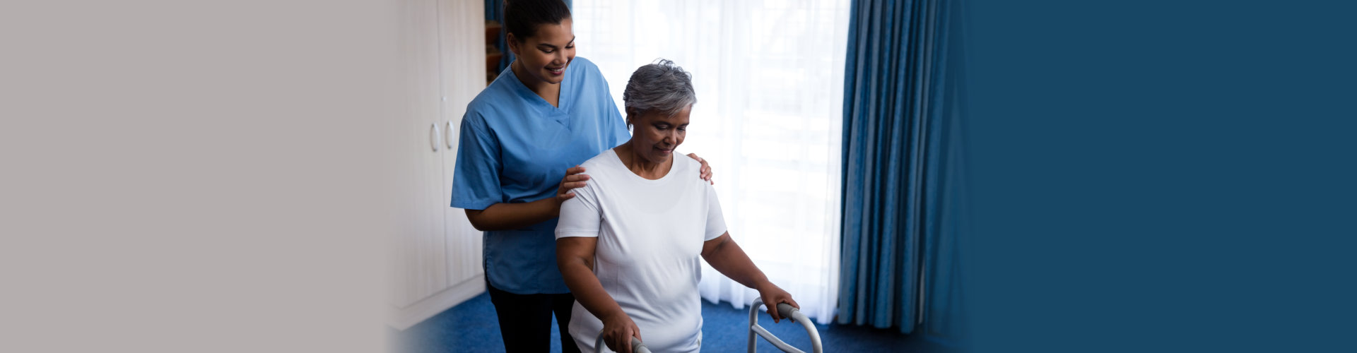 Nurse hepling senior women in walking with walker at nursing home